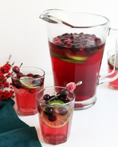 two glasses filled with red wine and cranberry punch next to some cherries