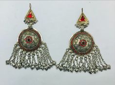 * This astonishing handpicked pair of tribal vintage earrings is a traditional ornament, stylish and classy both. * The unique ethnic earrings are hand embellished with red glass stone inlays and finely carved archaic patterns, while the bottom of the pair is ornated with long dangling tassels. The elegant earrings are made with metal alloy and covered with rustic silver hues, flaunting all the tribal kuchi vibes. * These nomadic earrings are there to be styled in a truly wonderful way to stun o Traditional Festival Plug Earrings Nickel Free, Traditional Red Brass Earrings, Bohemian Earrings With Latkans For Festive Occasions, Vintage Round Earrings For Festivals, Traditional Metal Plug Earrings For Party, Traditional Drop Earrings Nickel Free, Traditional Drop Plug Earrings For Party, Bohemian Drop Earrings For Festive Season, Red Vintage Earrings For Festivals