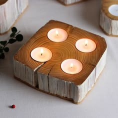 four lit candles sitting on top of a wooden block