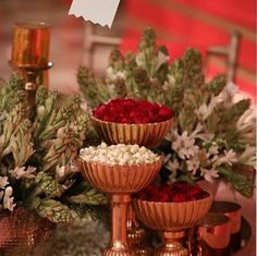 three gold bowls filled with flowers on top of a table