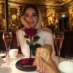 a woman sitting at a table with a rose in her hand