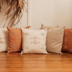 four pillows are lined up on the floor in front of a potted palm tree