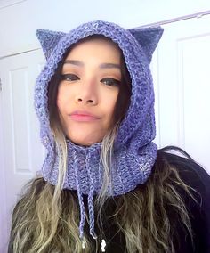 a woman wearing a purple knitted cat hat and scarf over her head with long hair