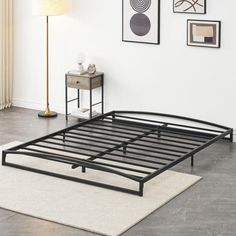 a black metal bed frame sitting on top of a white rug in front of a wall