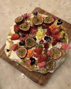 a cake decorated with fruit and flowers on a cutting board