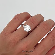 a woman's hand with a diamond ring on top of her finger, showing the center stone