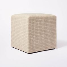 a small square ottoman sitting on top of a white floor