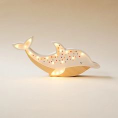 a light up whale is sitting on top of a wooden stand with its mouth open