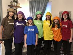 a group of young women standing next to each other in front of a window wearing colorful shirts