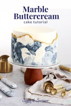 a marble buttercream cake on a stand with gold and silver utensils