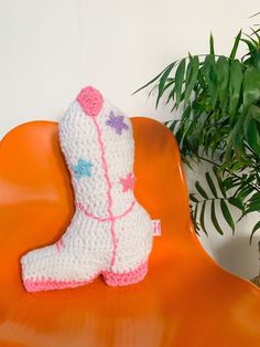 a crocheted boot sitting on an orange chair next to a potted plant