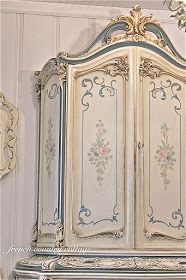 an ornate white and blue armoire with flowers on it