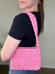 a woman holding a pink crocheted purse