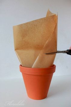 a person cutting paper in to a flower pot