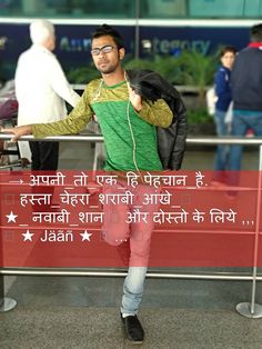 a man with headphones standing in front of an airport gate and holding his hand up