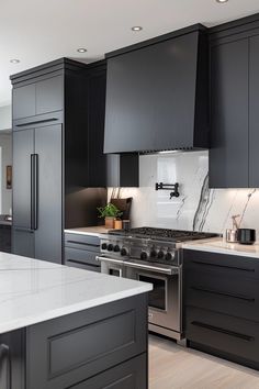 a kitchen with black cabinets and white counter tops, stainless steel appliances and an island