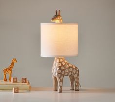 a giraffe lamp sitting on top of a table next to a stack of books