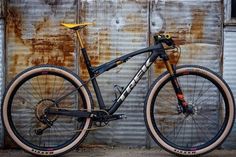 a bike leaning against a rusted building with the wheels still on it's rims