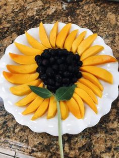 a white plate topped with sliced fruit and a blackberries centerpiece on top of a granite counter