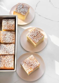 several pieces of cake sitting on plates next to each other with powdered sugar on top