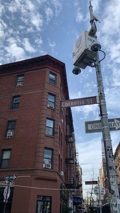 a street sign with a camera attached to it's pole in front of a building