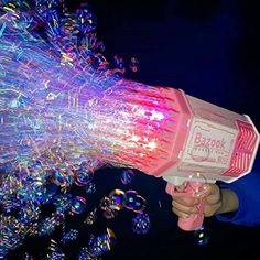 a person holding a pink and white blow dryer in their hand with bubbles coming out of it