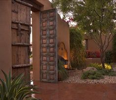 an open door leading into a courtyard with plants and flowers on the outside, in front of a house