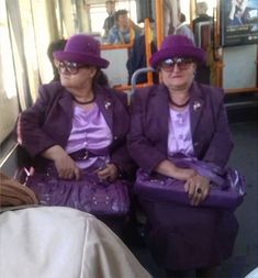 two women in purple outfits sitting on a bus