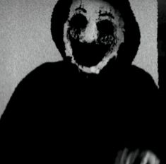 a creepy clown wearing a black hoodie and holding a cell phone in his hand