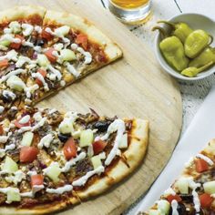 two pizzas with different toppings are on a cutting board next to some pickles