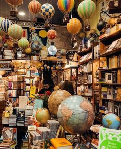 a room filled with lots of books and globes hanging from the ceiling in front of it