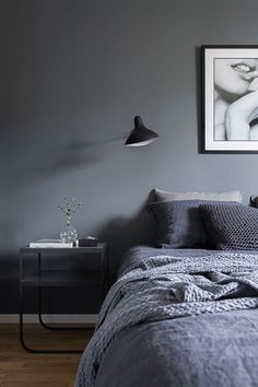 a bedroom with grey walls and wooden flooring has a gray comforter on the bed