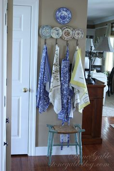 a bunch of towels hanging on the wall next to a table with plates and bowls