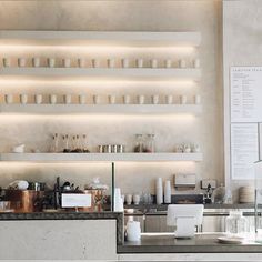 a coffee shop counter with cups and saucers on the shelves above it, along with other items