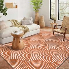 an orange and white rug in a living room with chairs, couches and potted plants