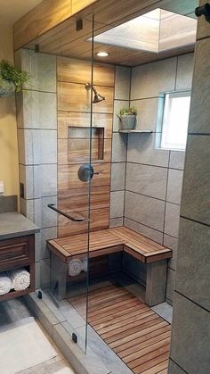 a walk in shower sitting next to a sink and a wooden bench inside of a bathroom