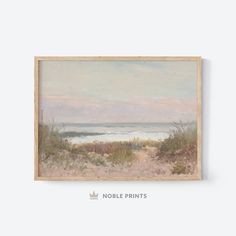 an oil painting of the ocean and sand dunes in front of a white wall with a wooden frame