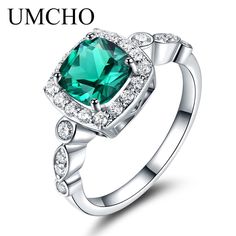 a green ring with diamonds on the sides and an oval shaped emerald stone in the center