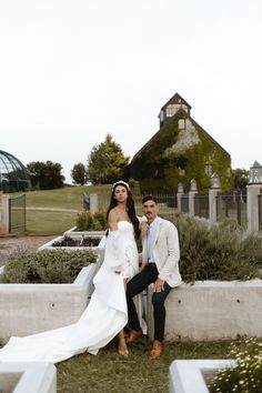 a man and woman posing for a photo in front of a cemetery