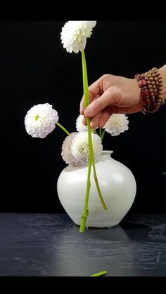 a person is arranging flowers in a white vase