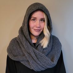 a woman with blonde hair wearing a gray crochet scarf and black hoodie