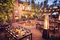 an outdoor dining area with tables, chairs and lights on the patio at night time