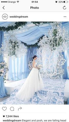 a woman in a white wedding dress standing next to a blue and white backdrop with chandeliers