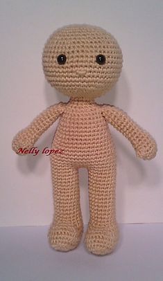 a crocheted doll is posed on a white surface