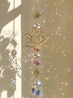 a wind chime hanging from a chain on a wall with sun shining through it