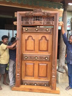 two men are holding up a large wooden door