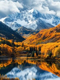 the mountains are covered in snow and fall foliage, with trees reflecting in the water