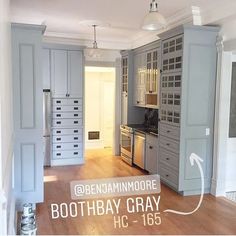 an empty kitchen with gray cabinets and wood flooring in the center is labeled below