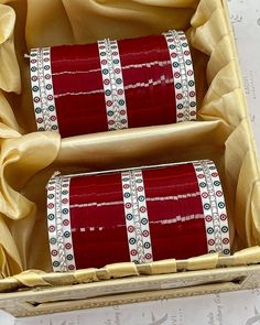 two rolls of red ribbon in a wooden box with gold ribbons on the inside and outside