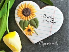 a heart shaped cookie decorated with sunflowers and writing paper on a slate board